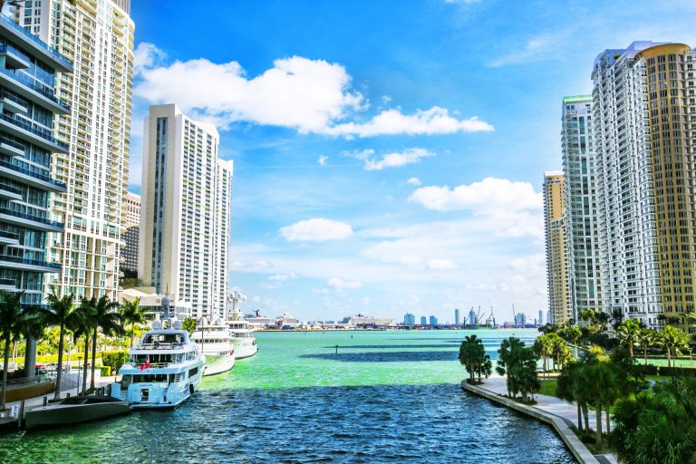 View of Miami's waterfront with high-rise buildings and yachts along the waterway.